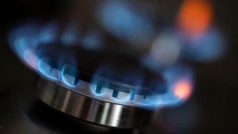 Auf einem Gasherd kommen blaue Flammen aus dem Brenner