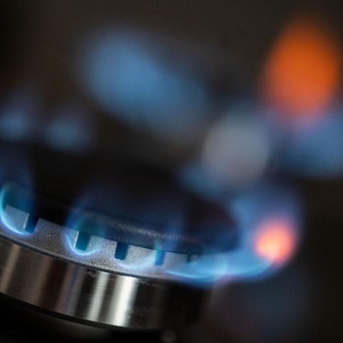 Auf einem Gasherd kommen blaue Flammen aus dem Brenner