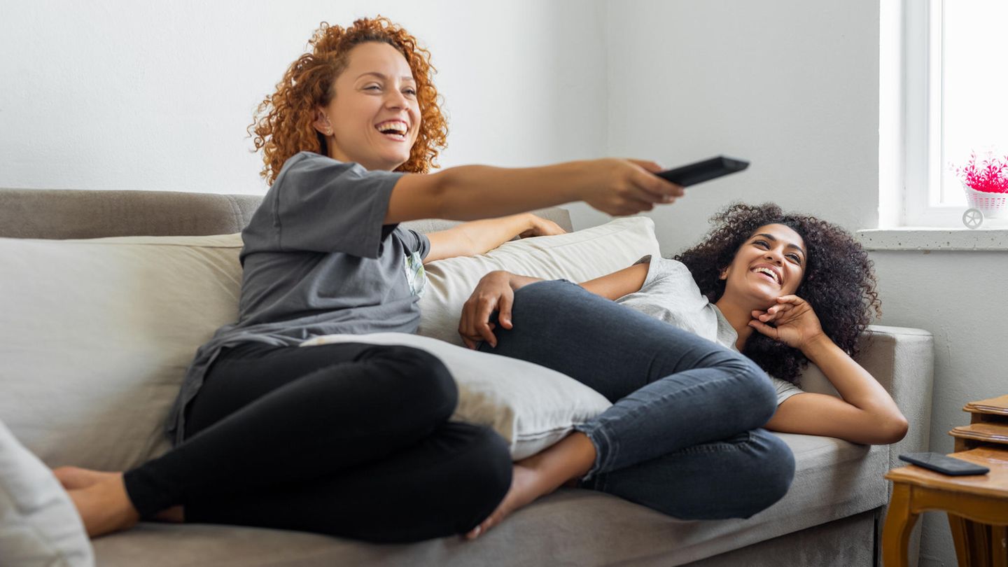 Zwei Frauen amüsieren sich auf dem Sofa gemeinsam.