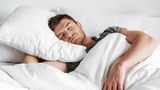 Ein Mann schläft in seinem Bett.
