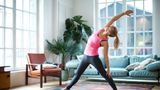 Eine Frau macht Yoga in ihrem Wohnzimmer.