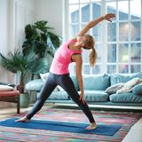 Eine Frau macht Yoga in ihrem Wohnzimmer.