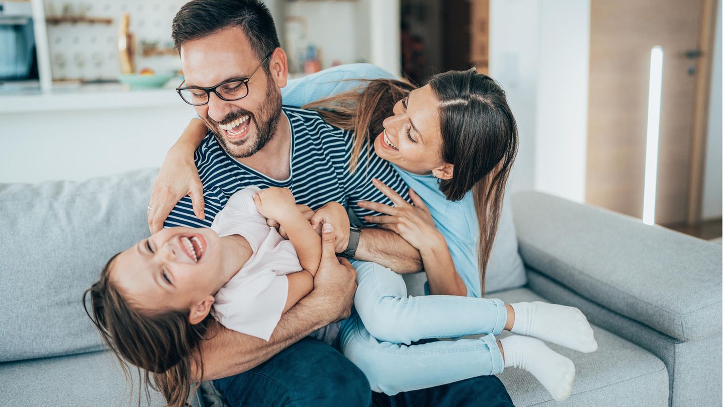 Mutter und Vater lachen mit Kind auf Schoß