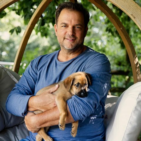 Hundetrainer Martin Rütter lächelt in einem Garten in die Kamera