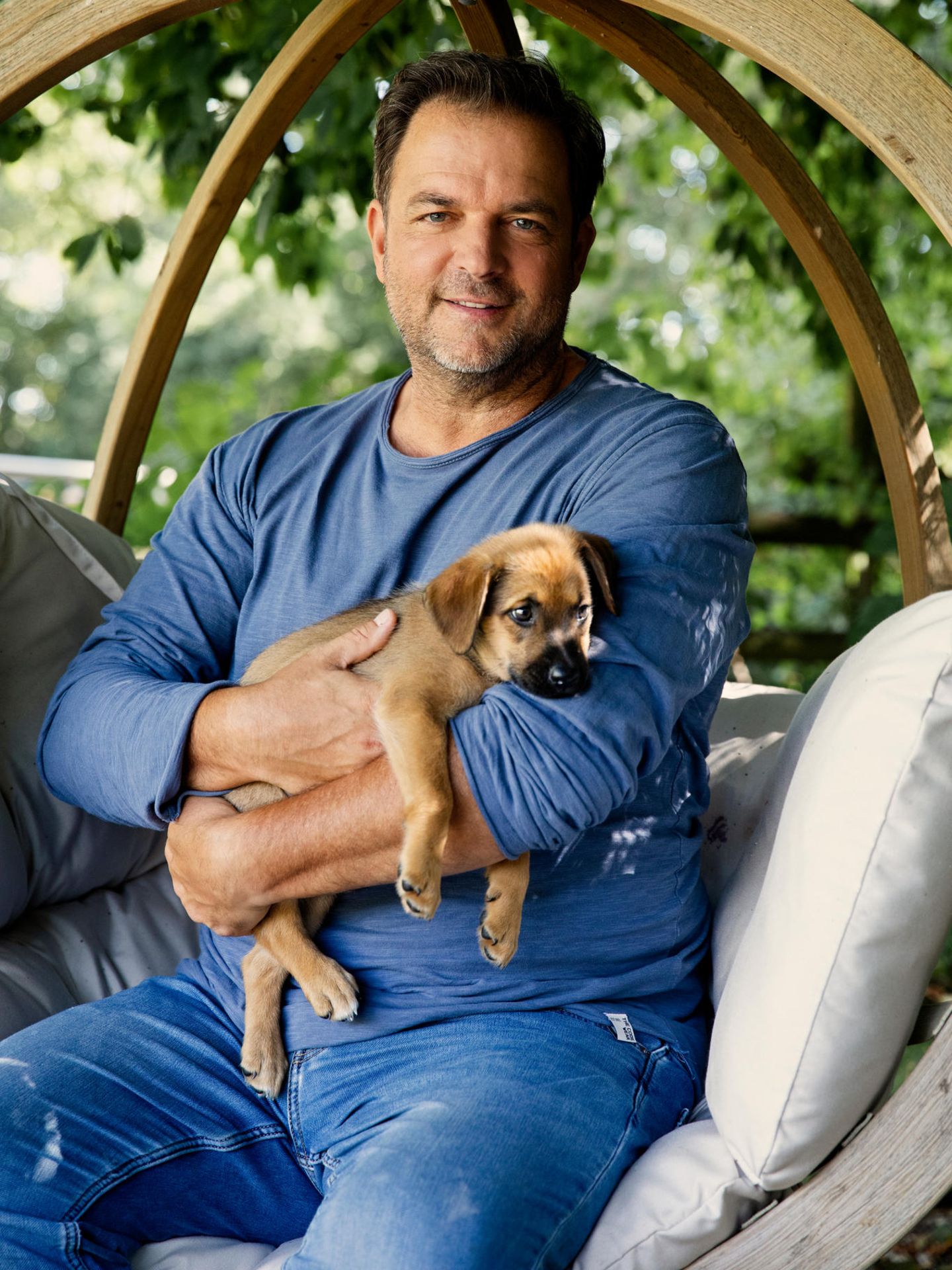 Hundetrainer Martin Rütter lächelt in einem Garten in die Kamera