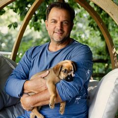 Hundetrainer Martin Rütter lächelt in einem Garten in die Kamera