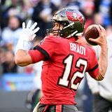 Ein weißer Mann in rotem Football-Dress holt mit einem Football in der rechten Hand zum Wurf aus