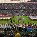Auf dem Rasen der zum Football-Stadion umgebauten Allianz-Arena halten Uniformierte eine riesige US-Flagge