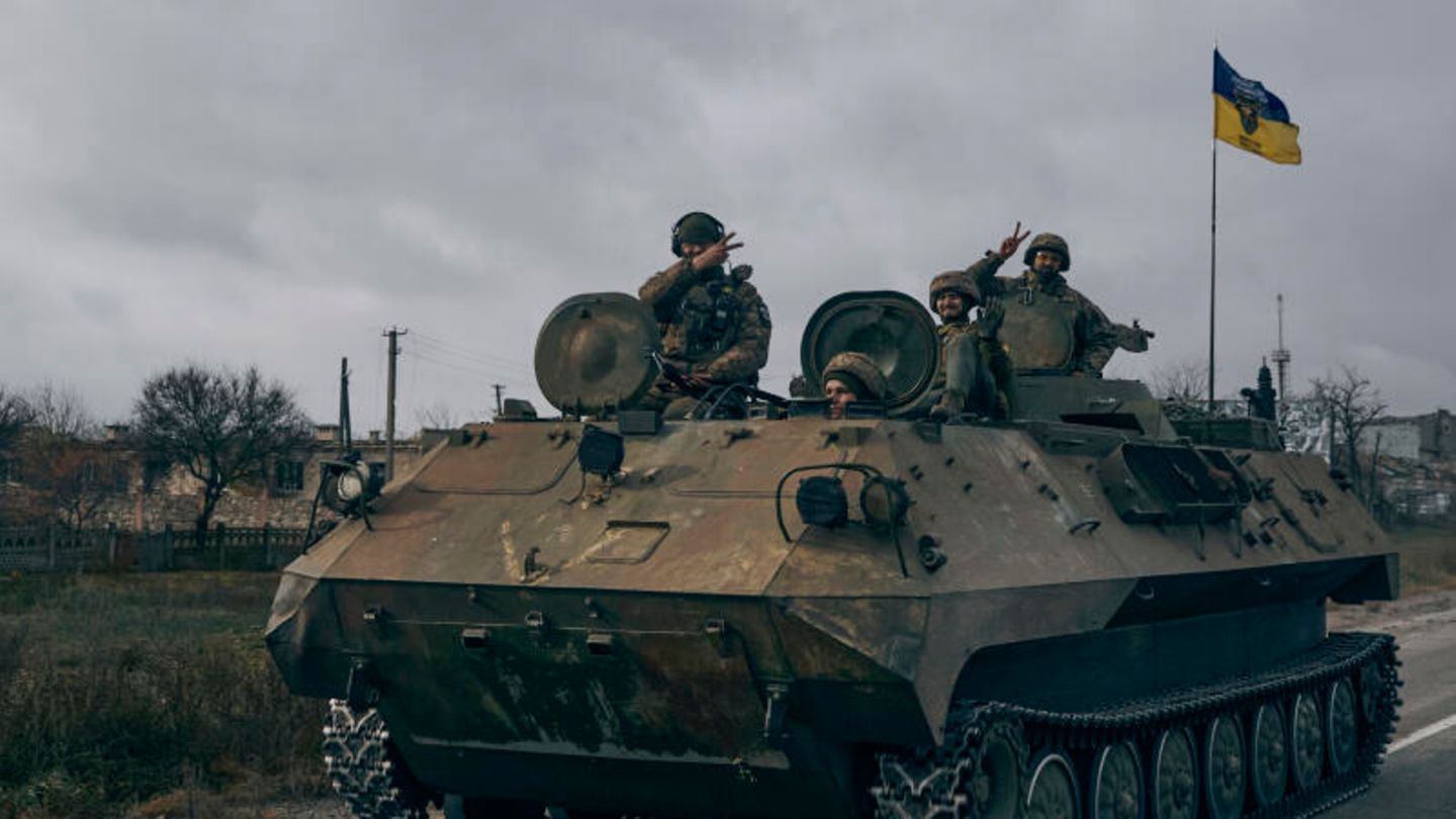 Ukrainische Soldaten zeigen ein Peace-Zeichen während sie mit einem erbeuteten russischen Schützenpanzer fahren Ukrainische Soldaten zeigen ein Peace-Zeichen während sie mit einem erbeuteten russischen Schützenpanzer fahren