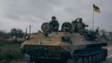 Ukrainische Soldaten zeigen ein Peace-Zeichen während sie mit einem erbeuteten russischen Schützenpanzer fahren