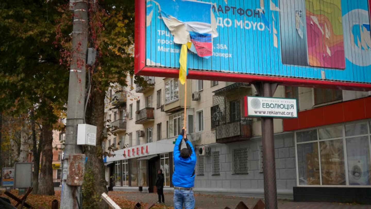 Ein Anwohner entfernt die russische Flagge von einer Plakatwand Ein Anwohner entfernt die russische Flagge von einer Plakatwand