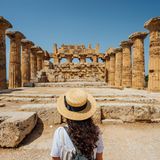 Eine Frau steht vor den antiken Ruinen in Athen.
