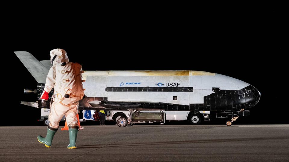 Ein Astronaut läuft auf die gelandete Boeing X-37B zu