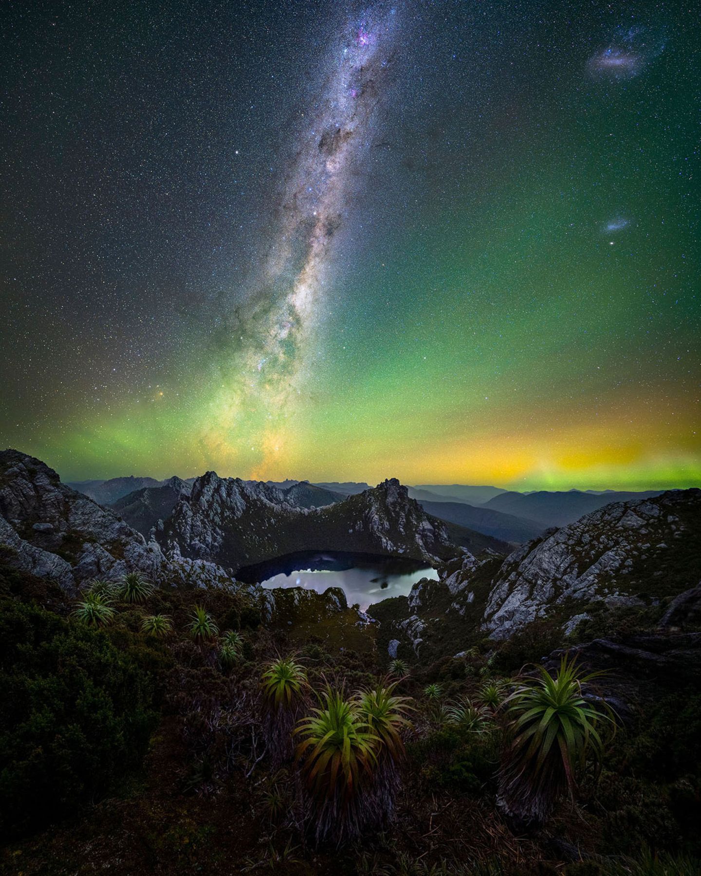 Über einem Bergsee strahlen Lichter in verschiedenen Farben am Nachthimmel