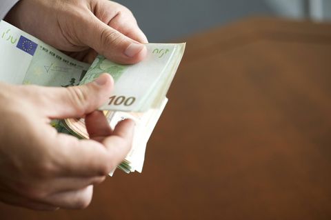 Nahaufnahme einer Hand, die mehrere Scheine Bargeld zählt