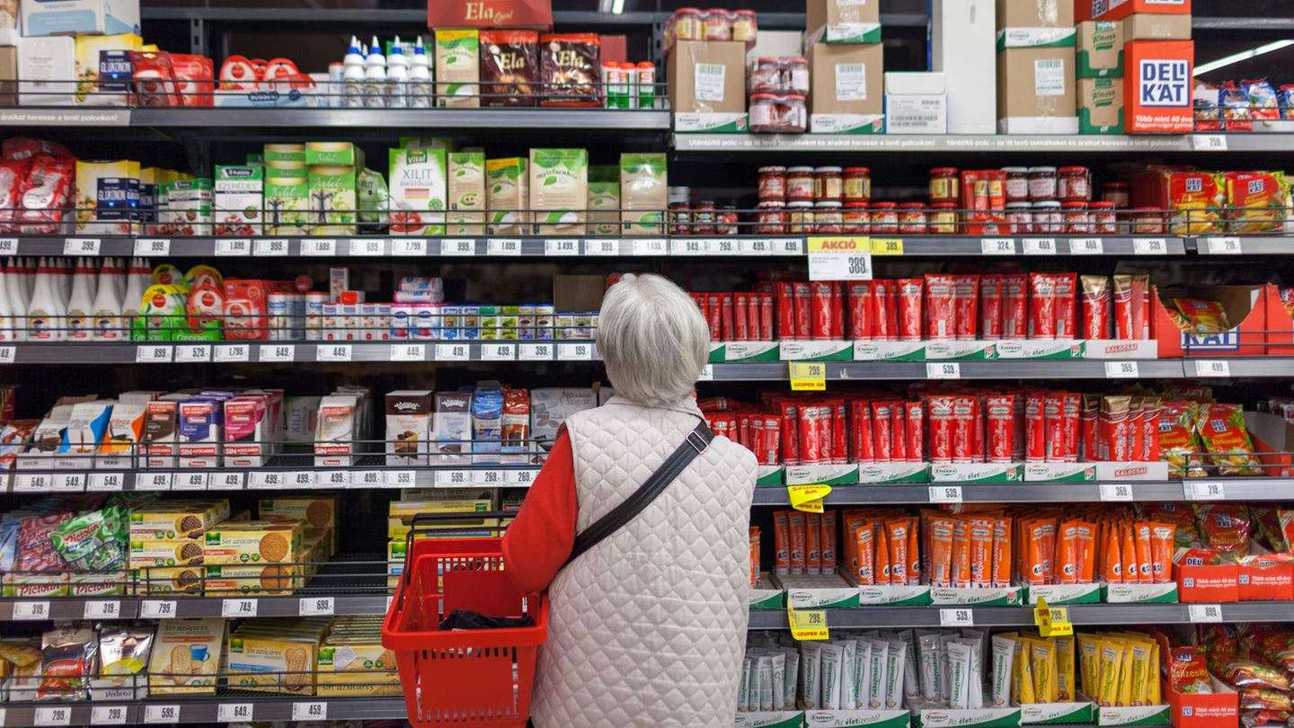 Eine Frau mit einem Warenkorb steht vor einem Regal in einem Lebensmittelgeschäft