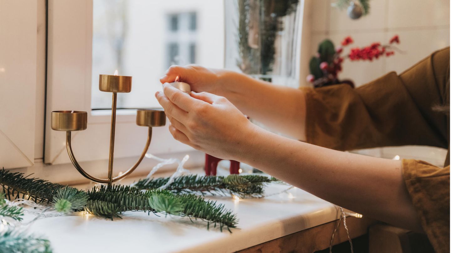Person dekoriert die Fensterbank mit Weihnachtsdeko
