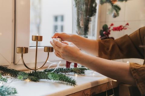 Person dekoriert die Fensterbank mit Weihnachtsdeko