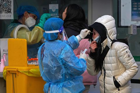 China: Eine Frau testet eine andere Frau auf Corona, indem sie einen Rachenabstrich nimmt