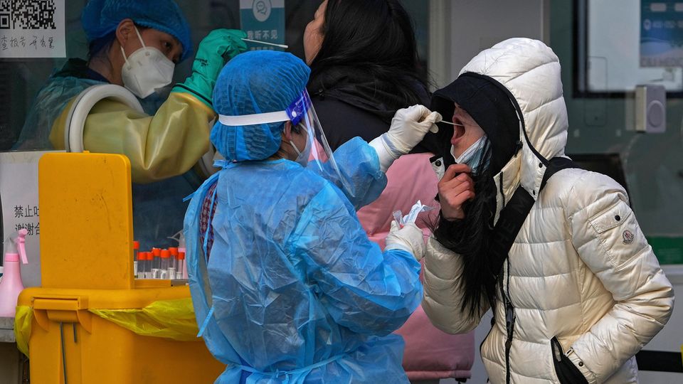 China: Eine Frau testet eine andere Frau auf Corona, indem sie einen Rachenabstrich nimmt