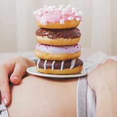 Donuts stapeln sich auf einem Bauch einer Schwangeren