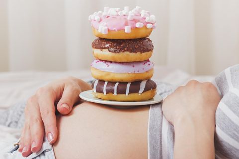 Donuts stapeln sich auf einem Bauch einer Schwangeren