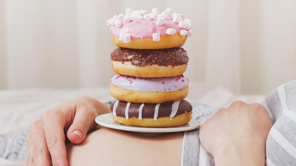 Donuts stapeln sich auf einem Bauch einer Schwangeren