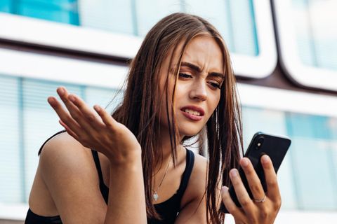Eine Frau schaut verwirrt auf ihr Handy