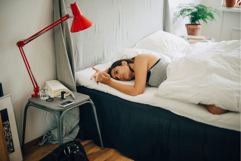 Frau prüft ihren Blutzucker während sie im Bett liegt