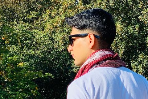 Ein junger Mann mit Sonnenbrille steht an einer Brücke
