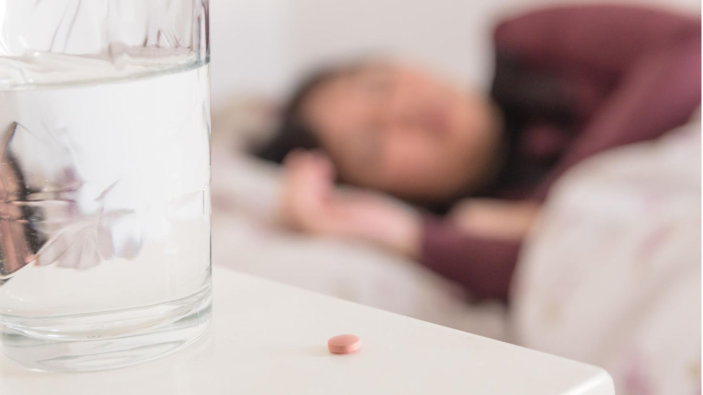 Frau im Bett mit Pille auf dem Nachtschrank Frau im Bett mit Pille auf dem Nachtschrank
