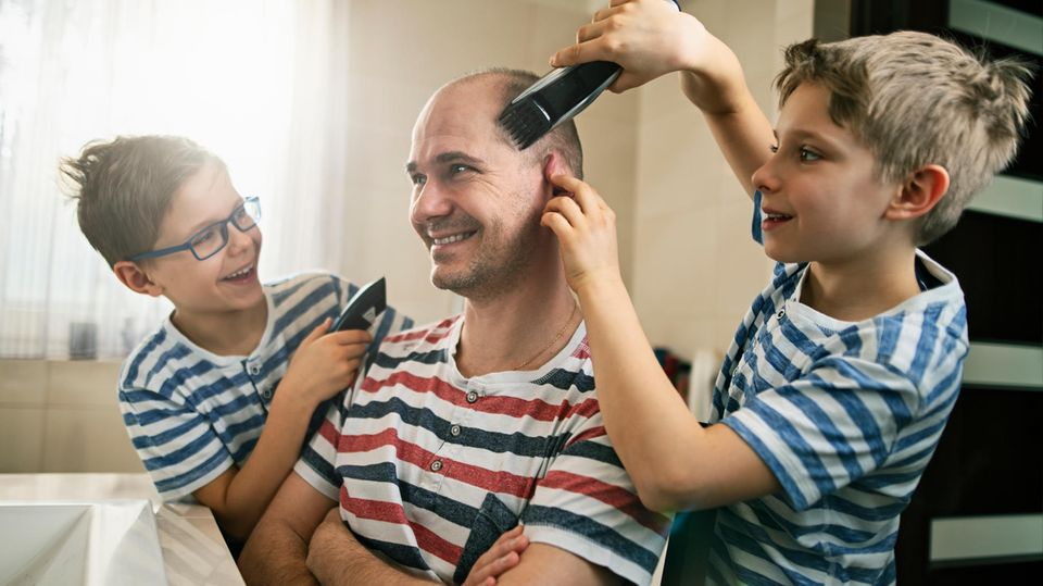 Jungen rasieren ihrem Vater den Kopf