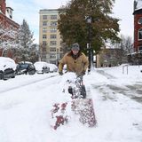 Ein Mann befreit einen Fußweg mit einer Schneefräse