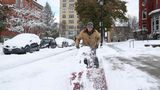 Ein Mann befreit einen Fußweg mit einer Schneefräse