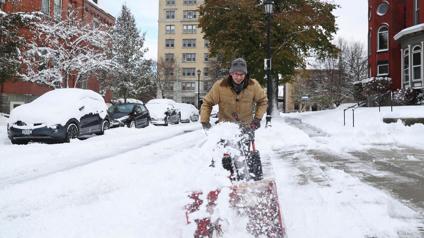 Ein Mann befreit einen Fußweg mit einer Schneefräse