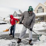 Zwei Männer räumen Schnee mit Schaufeln zur Seite