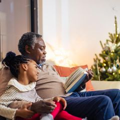 Mann liest Mädchen aus einem Weihnachtsbuch vor