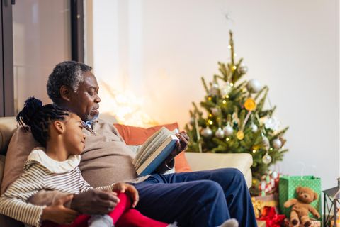 Mann liest Mädchen aus einem Weihnachtsbuch vor