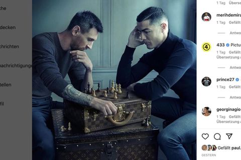 Lionel Messi und Cristiano Ronaldo sitzen sich gegenüber. Auf einem Koffer zwischen ihnen stehen Schachfiguren