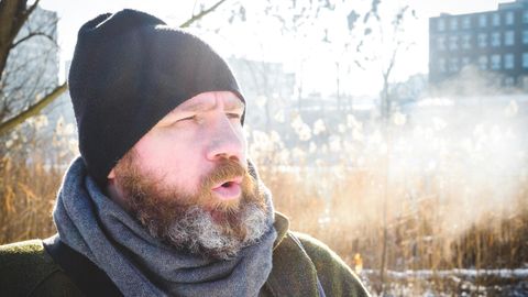 Ein Mann mit Schal und Mütze in einer Winterlandschaft