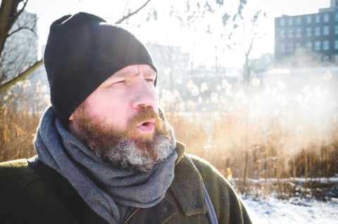 Ein Mann mit Schal und Mütze in einer Winterlandschaft
