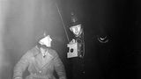 Ein Polizist hilft im dichten Smog von London einem Motorradfahrer