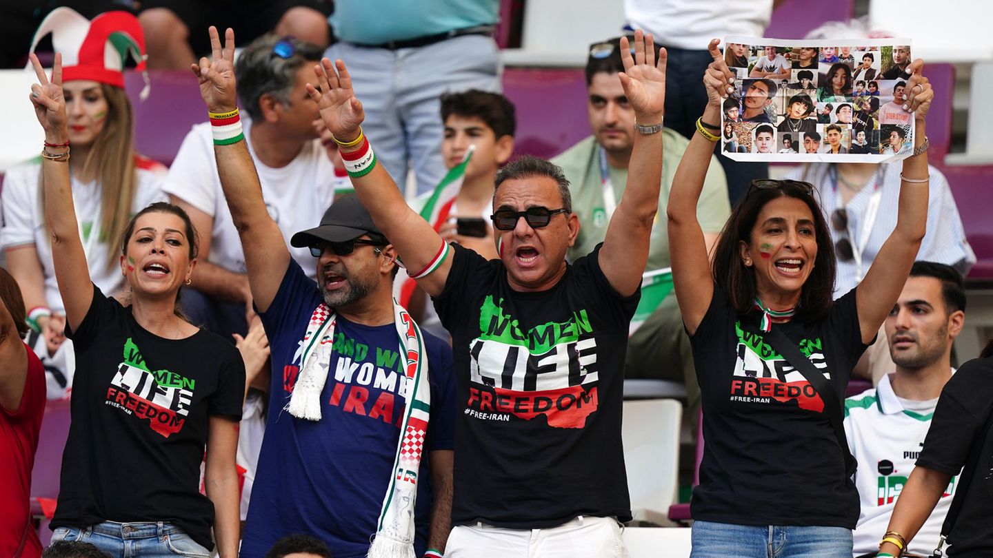 Iran-Fans auf der Tribüne tragen T-Shirts mit der Aufschrift "Women Life Freedom" – und zeigen das Peace-Zeichen.