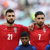 Während die Hymne der iranischen Republik im Stadion abgespielt wird, schweigen die iranischen Spieler. Stattdessen hört man deutlich Pfiffe von den Rängen, die dem Regime in Teheran gelten.