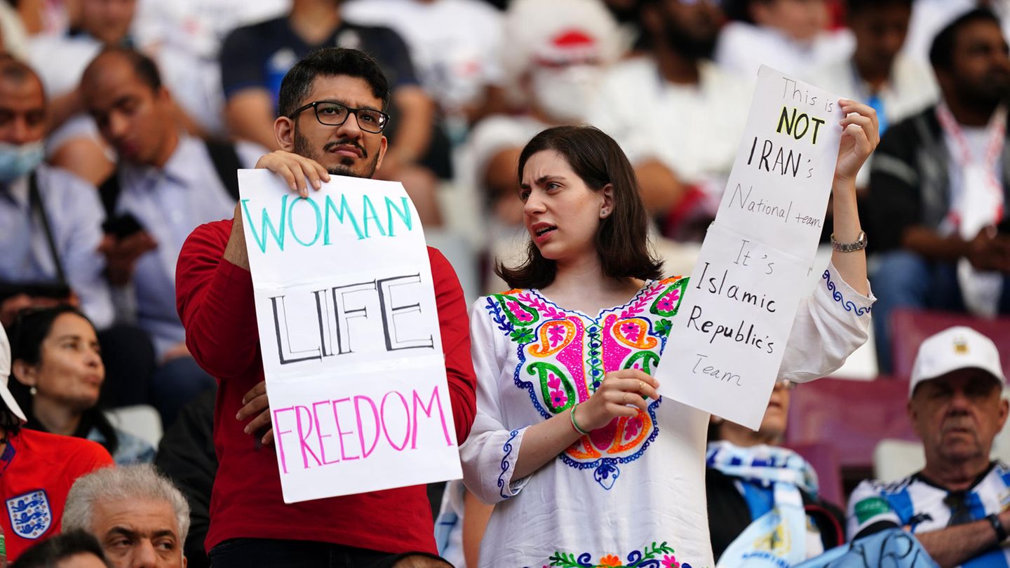 Auffallend viele Frauen, die die iranische Mannschaft auf der Tribüne unterstützen, tragen kein Kopftuch. Im Iran gehen seit dem Tod der jungen Kurdin Mahsa Amini am 16. September landesweit Menschen gegen die Führung in Teheran auf die Straße. Die 22-Jährige war von der Sittenpolizei festgenommen worden, weil sie ihr islamisches Kopftuch nicht ordnungsgemäß getragen haben soll.