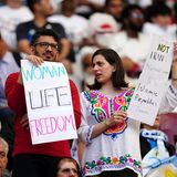 Auffallend viele Frauen, die die iranische Mannschaft auf der Tribüne unterstützen, tragen kein Kopftuch. Im Iran gehen seit dem Tod der jungen Kurdin Mahsa Amini am 16. September landesweit Menschen gegen die Führung in Teheran auf die Straße. Die 22-Jährige war von der Sittenpolizei festgenommen worden, weil sie ihr islamisches Kopftuch nicht ordnungsgemäß getragen haben soll.