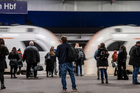 Fahrgäste stehen vor einem einfahrenden ICE