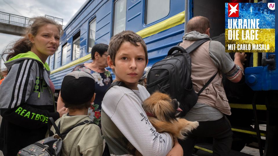 Ein Junge hält seinen Hund im Arm, als er mit Familienmitgliedern einen Zug besteigt
