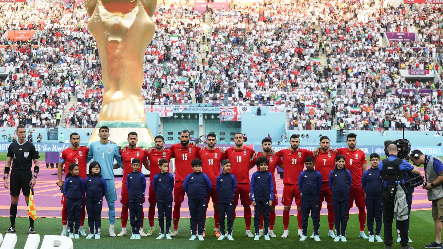 Iran's players stand in front of the oversized World Cup trophy during the national anthem