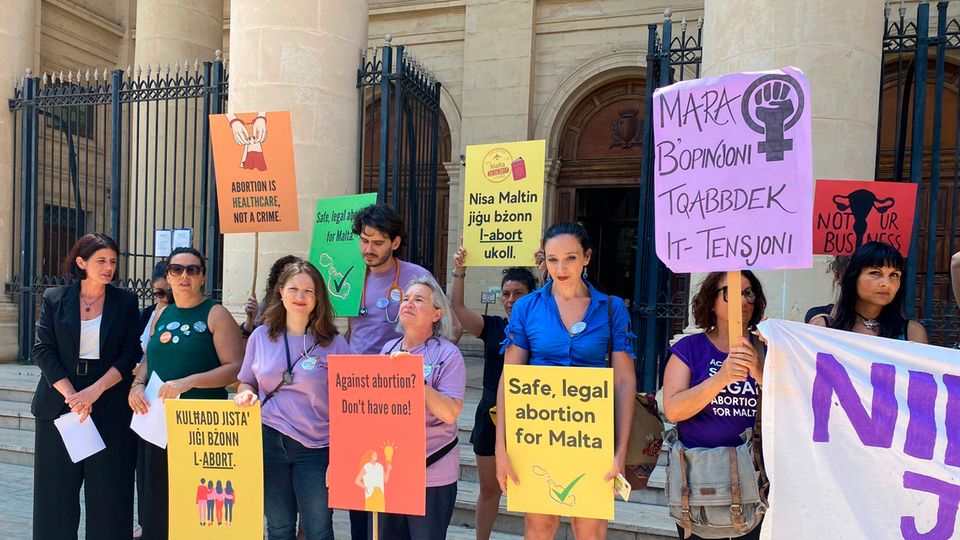 Protestierende mit Schildern stehen vor dem Gericht in Valletta, Malta